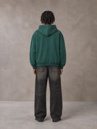 Model wearing the SM Monkey Wash Hoodie in Alpine Green, rear view.