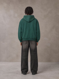 Model wearing the SM Monkey Wash Hoodie in Alpine Green, rear view.