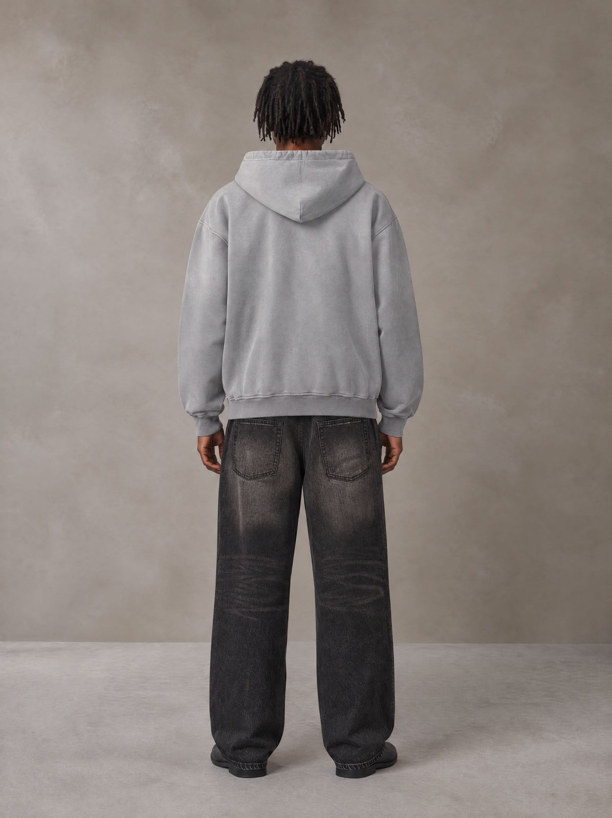 Model wearing the SM Monkey Wash Hoodie in Pure Grey, rear view.