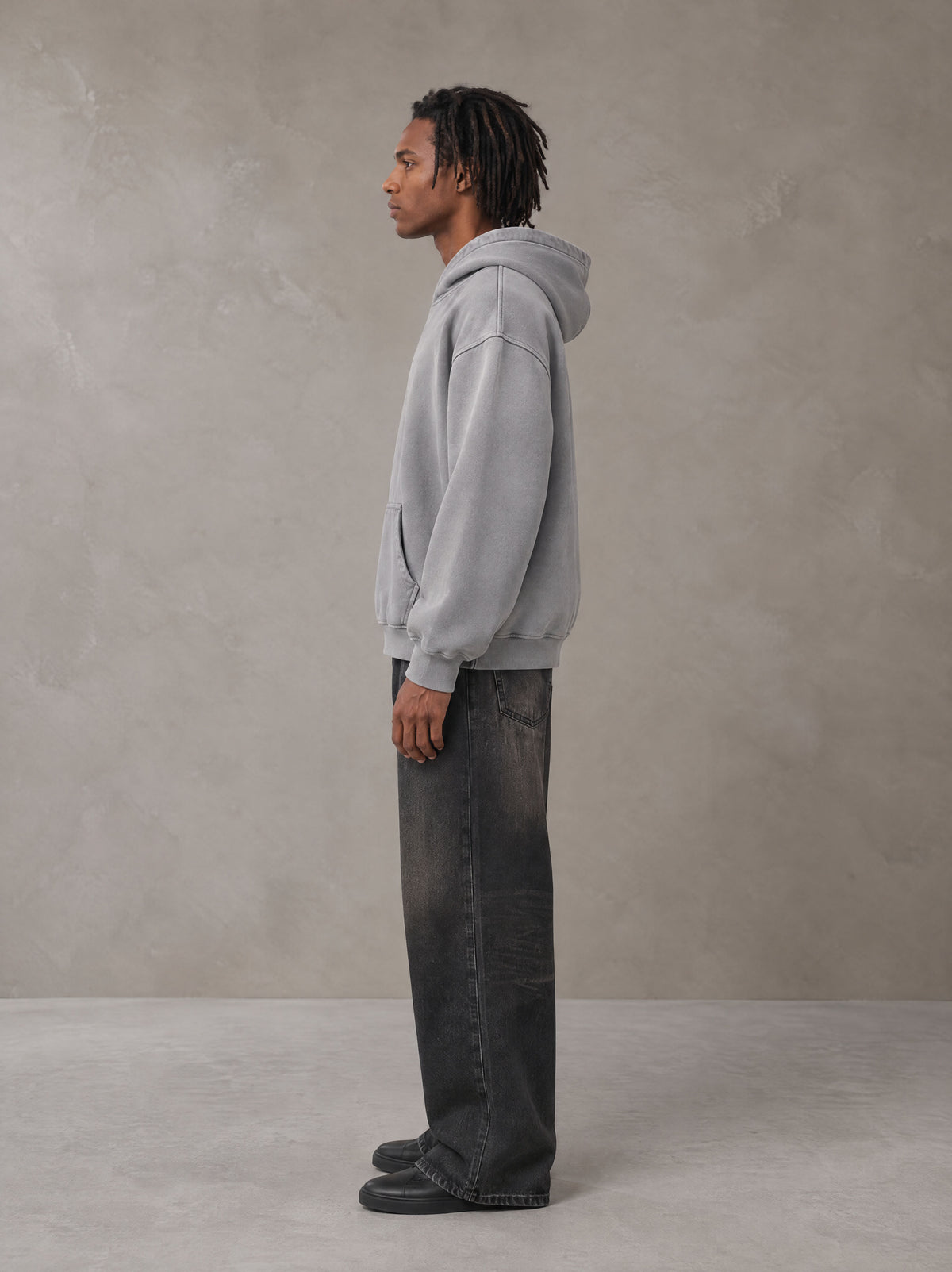 Model wearing the SM Monkey Wash Hoodie in Pure Grey, side profile.