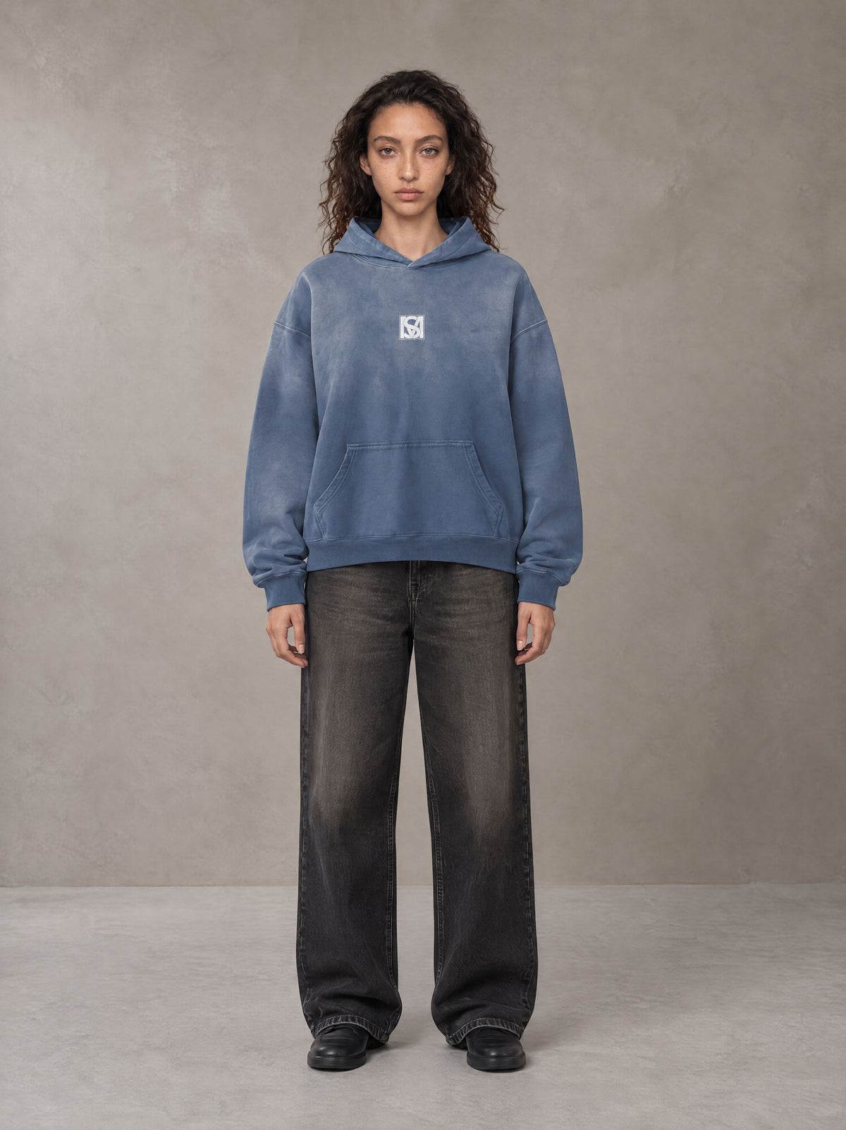 Model wearing the SM Monkey Wash Hoodie in Chambray, front view.
