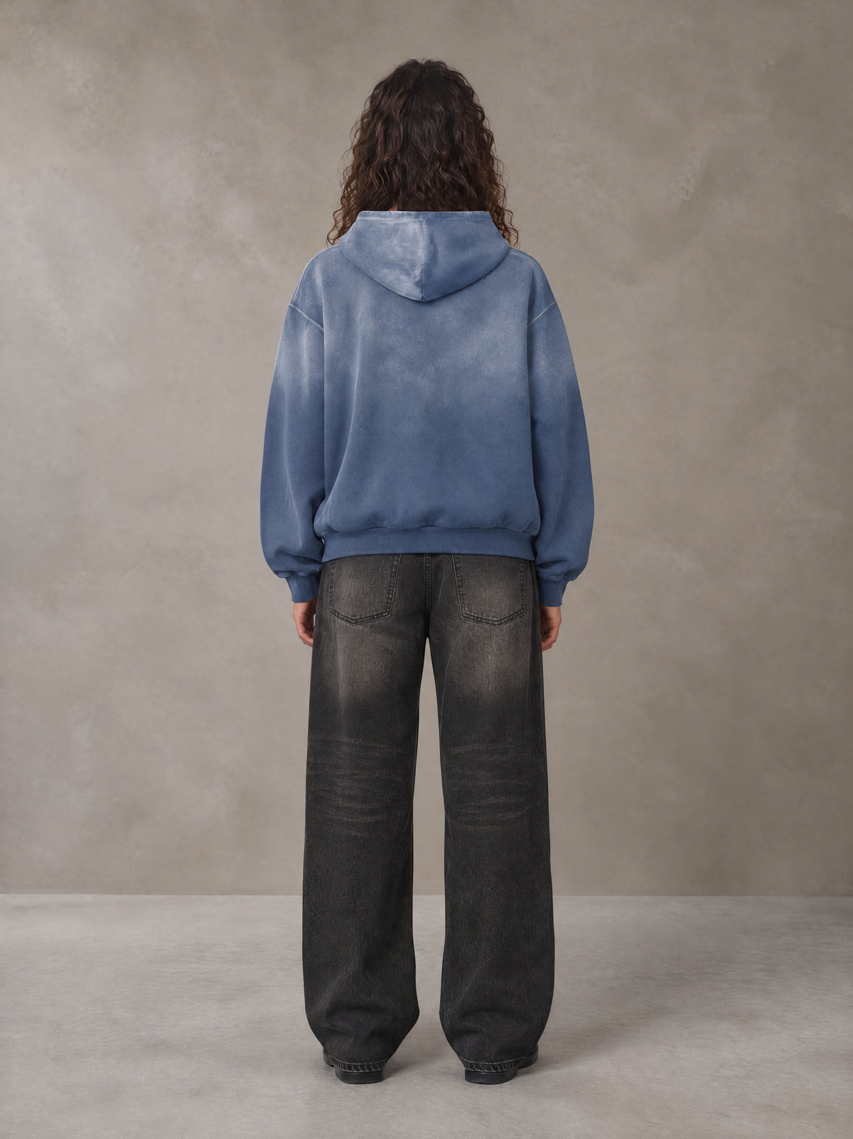 Model wearing the SM Monkey Wash Hoodie in Chambray, rear view.