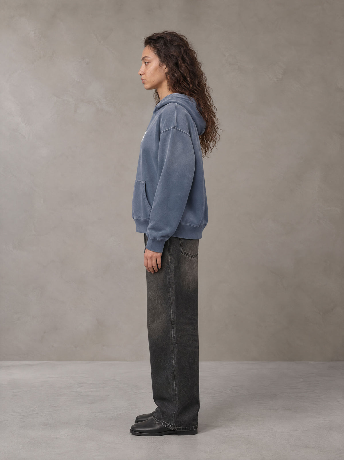 Model wearing the SM Monkey Wash Hoodie in Chambray, side profile.