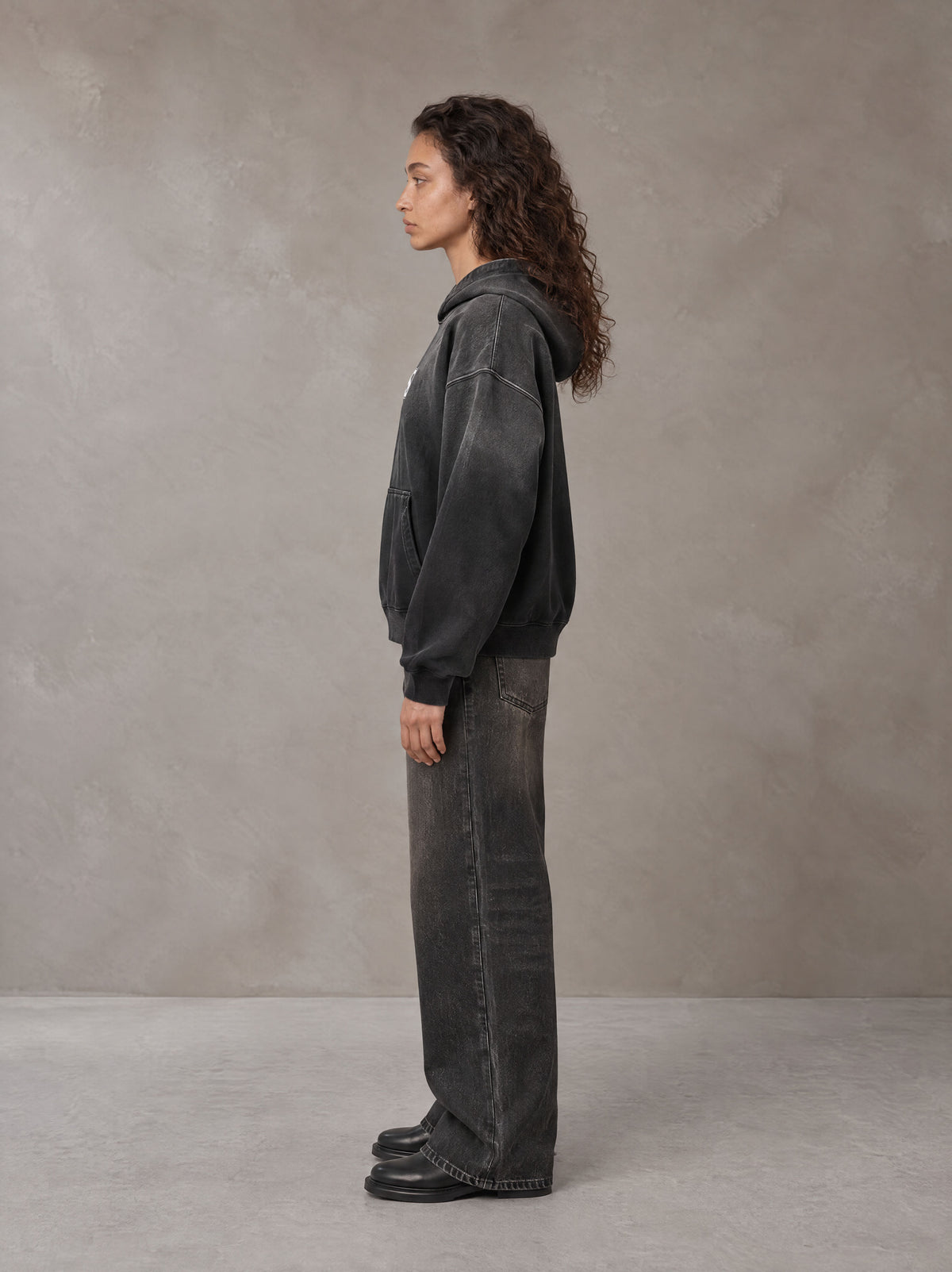 Model wearing the SM Monkey Wash Hoodie in Midnight Black, side profile.