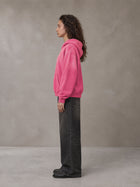 Model wearing the SM Monkey Wash Hoodie in Vivid Pink, side profile.