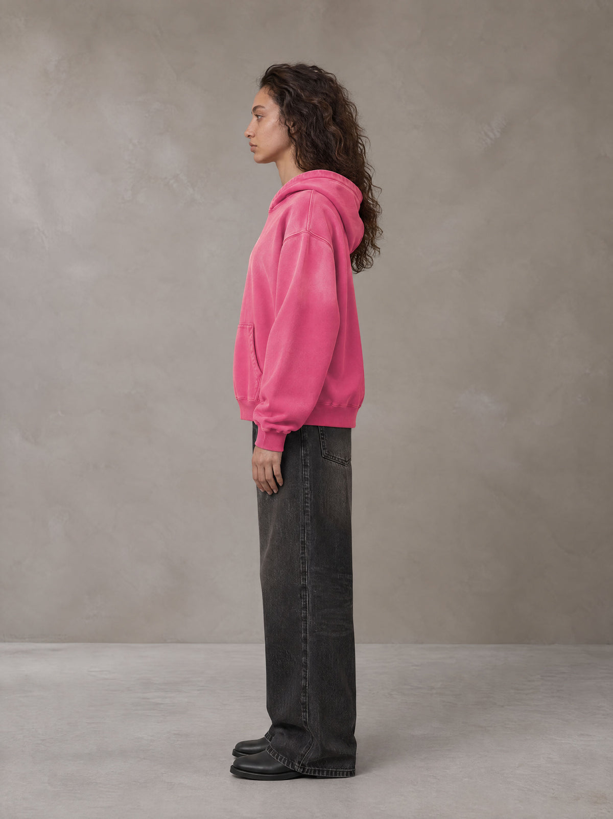 Model wearing the SM Monkey Wash Hoodie in Vivid Pink, side profile.