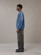 Model wearing the SM Monkey Wash Sweatshirt in Deep Denim, side profile.