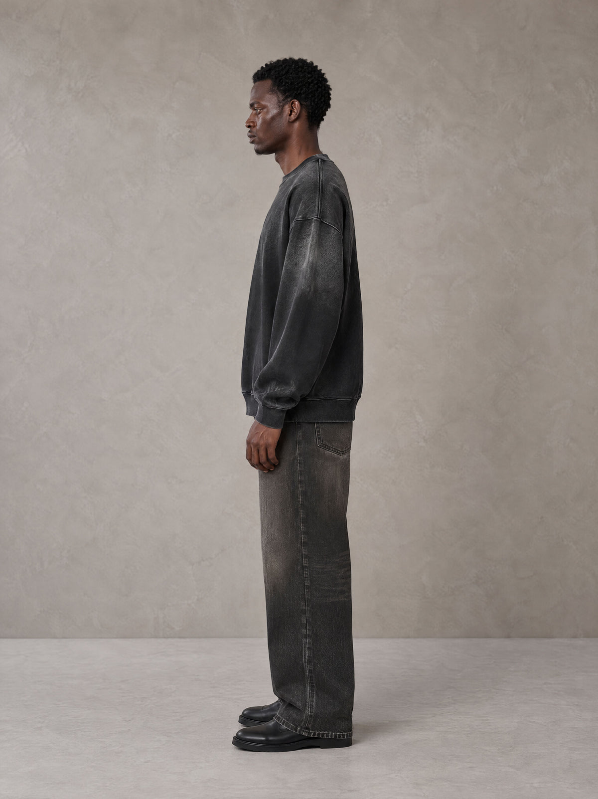 Model wearing the SM Monkey Wash Sweatshirt in Midnight Black, side profile.