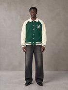 Model wearing the SM Varsity Baseball Jacket in Eden Green, front view.