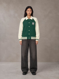 Model wearing the SM Varsity Baseball Jacket in Eden Green, front view.