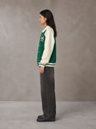 Model wearing the SM Varsity Baseball Jacket in Eden Green, side profile.