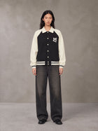 Model wearing the SM Varsity Baseball Jacket in Midnight Black, front view.