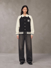 Model wearing the SM Varsity Baseball Jacket in Midnight Black, front view.