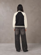 Model wearing the SM Varsity Baseball Jacket in Midnight Black, rear view.