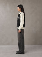 Model wearing the SM Varsity Baseball Jacket in Midnight Black, side profile.