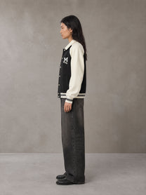 Model wearing the SM Varsity Baseball Jacket in Midnight Black, side profile.