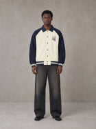 Model wearing the SM Varsity Baseball Jacket in Oxford Navy, front view.