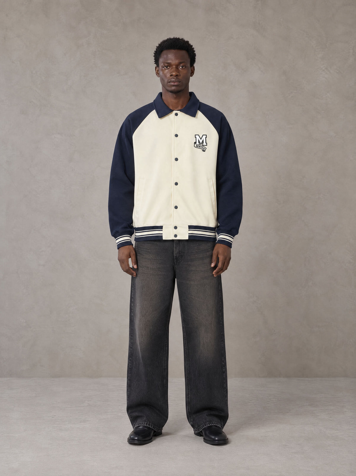 Model wearing the SM Varsity Baseball Jacket in Oxford Navy, front view.
