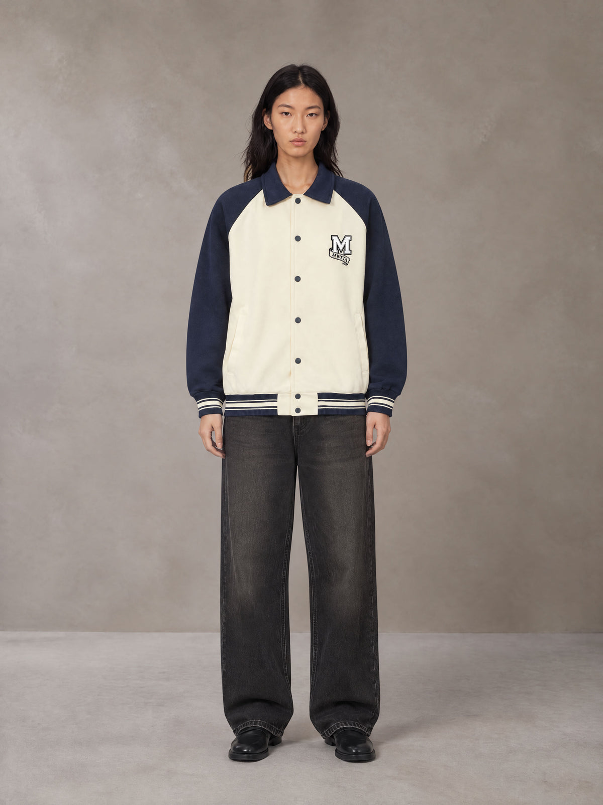 Model wearing the SM Varsity Baseball Jacket in Oxford Navy, front view.