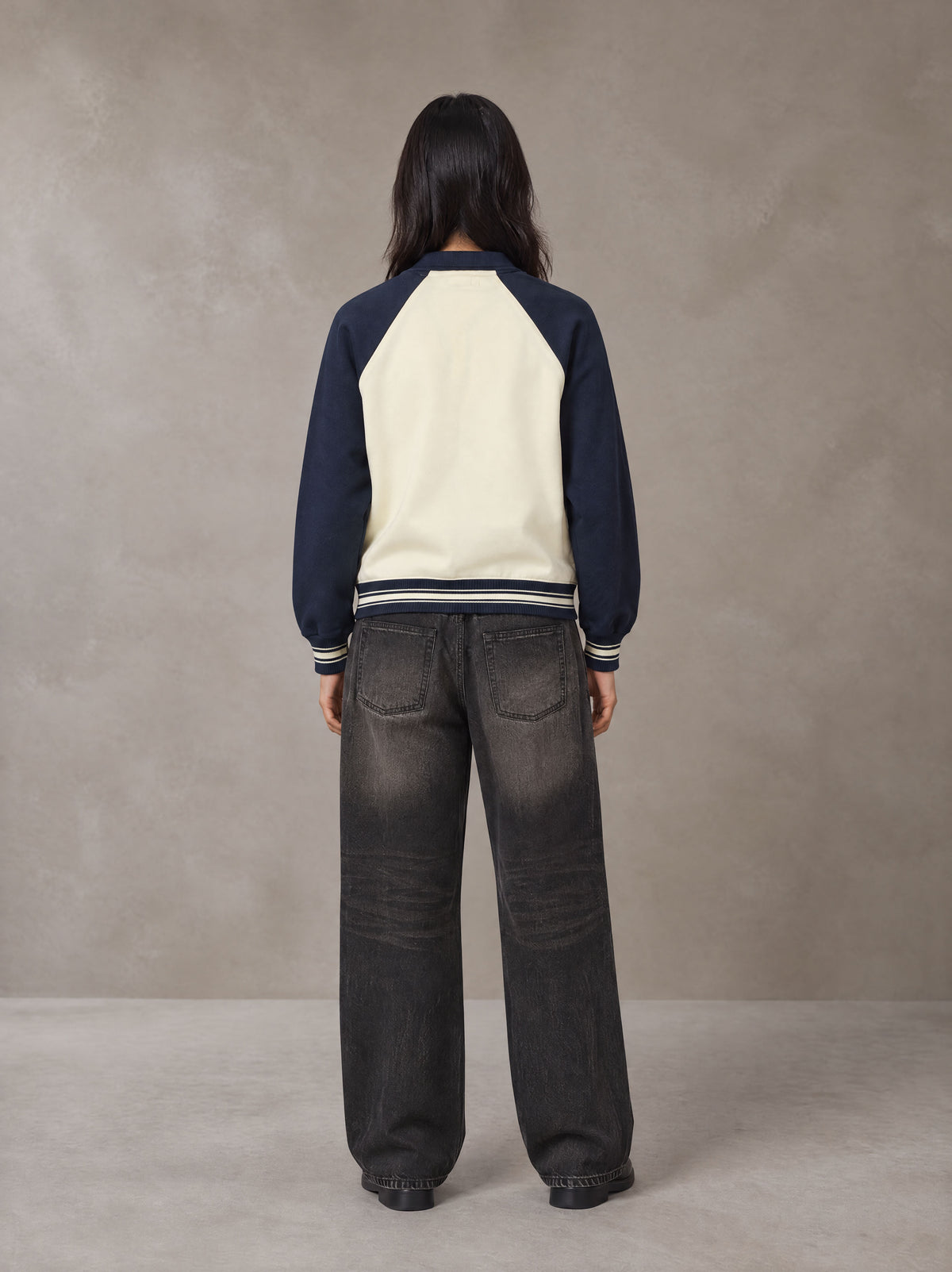 Model wearing the SM Varsity Baseball Jacket in Oxford Navy, rear view.