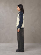 Model wearing the SM Varsity Baseball Jacket in Oxford Navy, side profile.