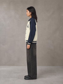 Model wearing the SM Varsity Baseball Jacket in Oxford Navy, side profile.
