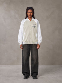 Model wearing the SM Varsity Jacket in Oatmeal Cookie, front view.