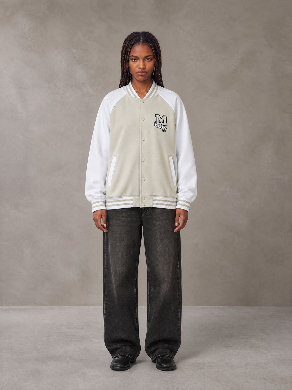 Model wearing the SM Varsity Jacket in Oatmeal Cookie, front view.