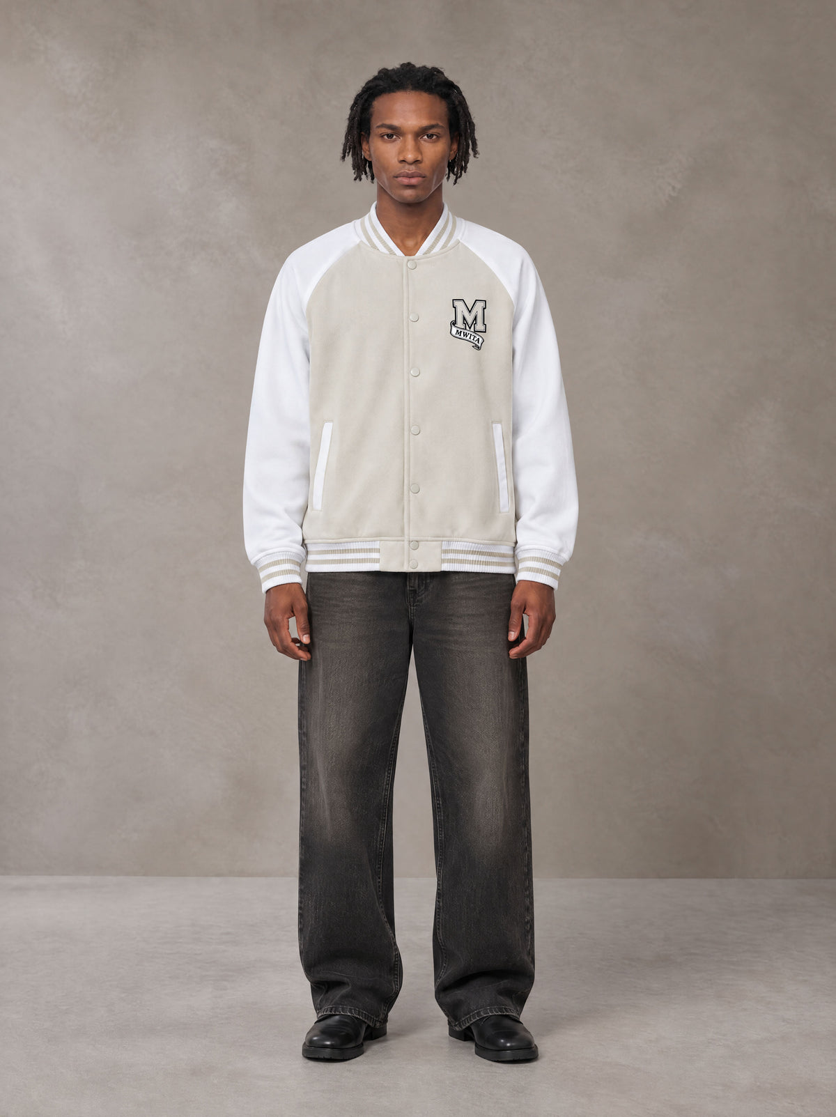 Model wearing the SM Varsity Jacket in Oatmeal Cookie, front view.