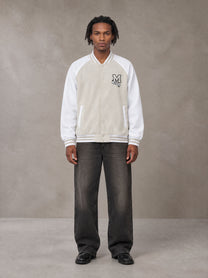 Model wearing the SM Varsity Jacket in Oatmeal Cookie, front view.