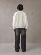 Model wearing the SM Varsity Jacket in Oatmeal Cookie, rear view.