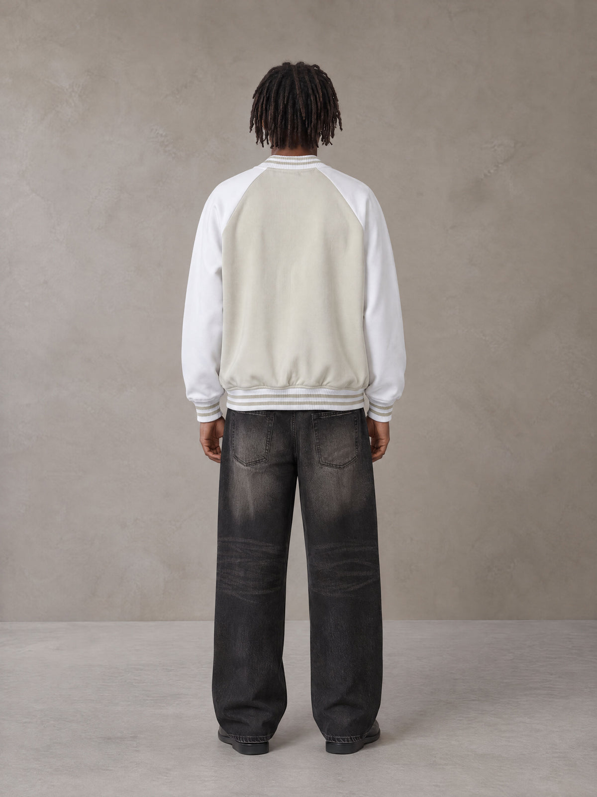 Model wearing the SM Varsity Jacket in Oatmeal Cookie, rear view.
