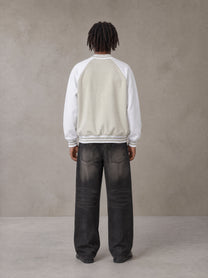 Model wearing the SM Varsity Jacket in Oatmeal Cookie, rear view.