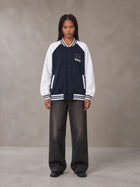 Model wearing the SM Varsity Jacket in Oxford Navy, front view.