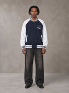 Model wearing the SM Varsity Jacket in Oxford Navy, front view.