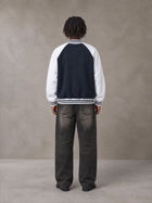 Model wearing the SM Varsity Jacket in Oxford Navy, rear view.