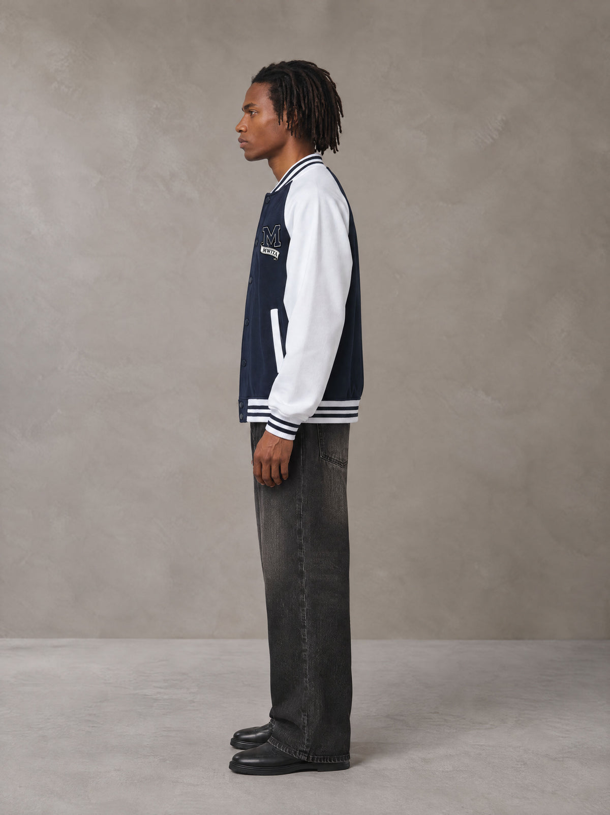 Model wearing the SM Varsity Jacket in Oxford Navy, side profile.