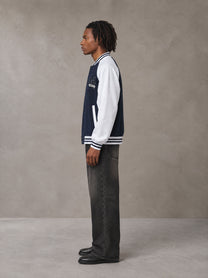 Model wearing the SM Varsity Jacket in Oxford Navy, side profile.
