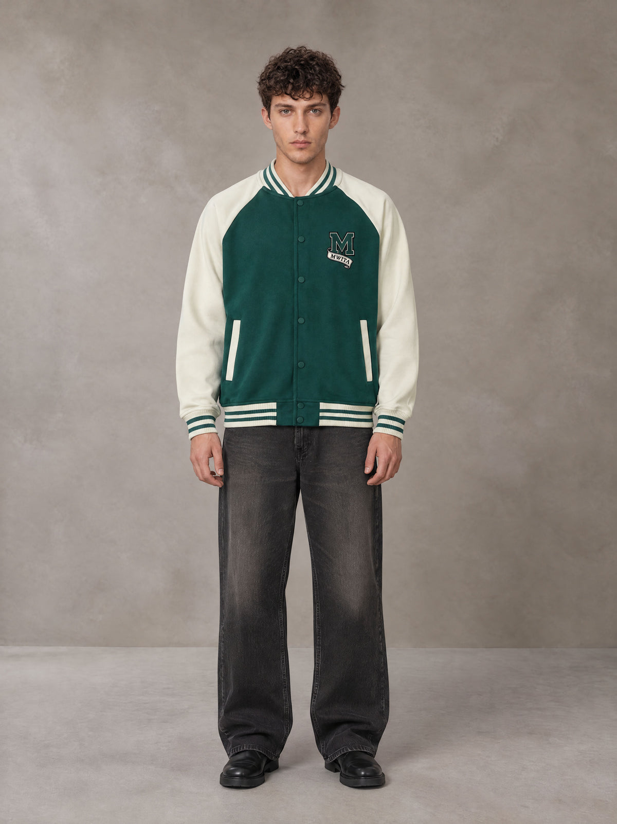 Model wearing the SM Varsity Jacket in Alpine Green, front view.