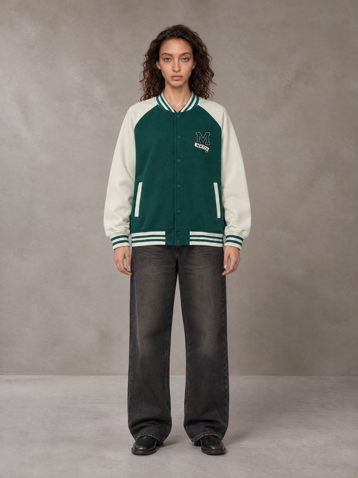 Model wearing the SM Varsity Jacket in Alpine Green, front view.