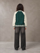 Model wearing the SM Varsity Jacket in Alpine Green, rear view.