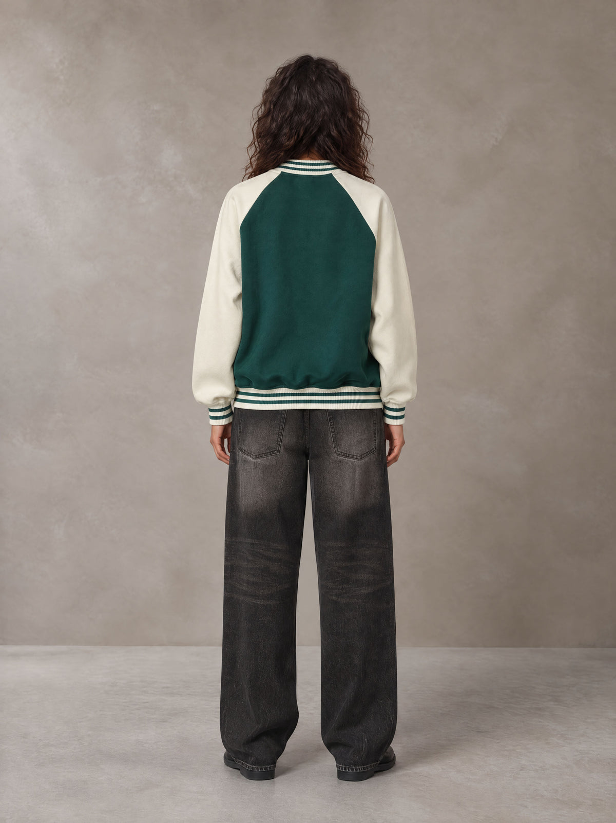 Model wearing the SM Varsity Jacket in Alpine Green, rear view.