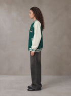 Model wearing the SM Varsity Jacket in Alpine Green, side profile.