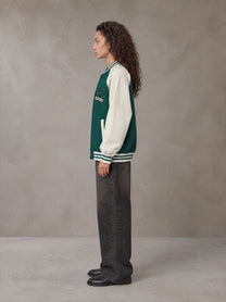 Model wearing the SM Varsity Jacket in Alpine Green, side profile.