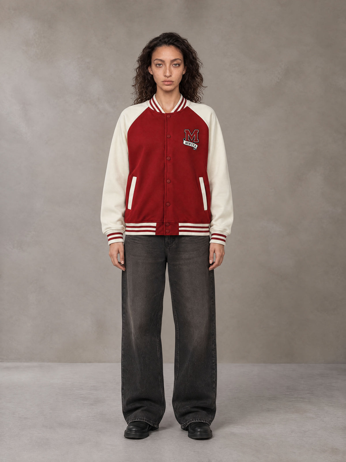 Model wearing the SM Varsity Jacket in Carmine, front view.