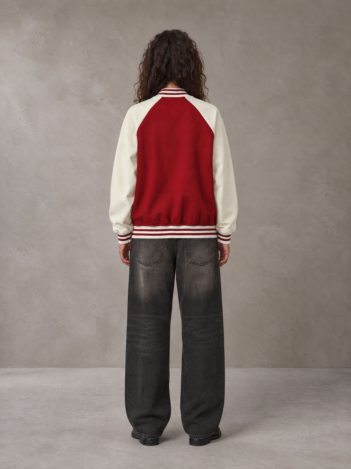 Model wearing the SM Varsity Jacket in Carmine, rear view.