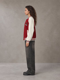 Model wearing the SM Varsity Jacket in Carmine, side profile.