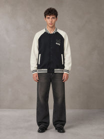 Model wearing the SM Varsity Jacket in Midnight Black, front view.