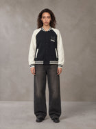 Model wearing the SM Varsity Jacket in Midnight Black, front view.