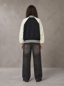 Model wearing the SM Varsity Jacket in Midnight Black, rear view.